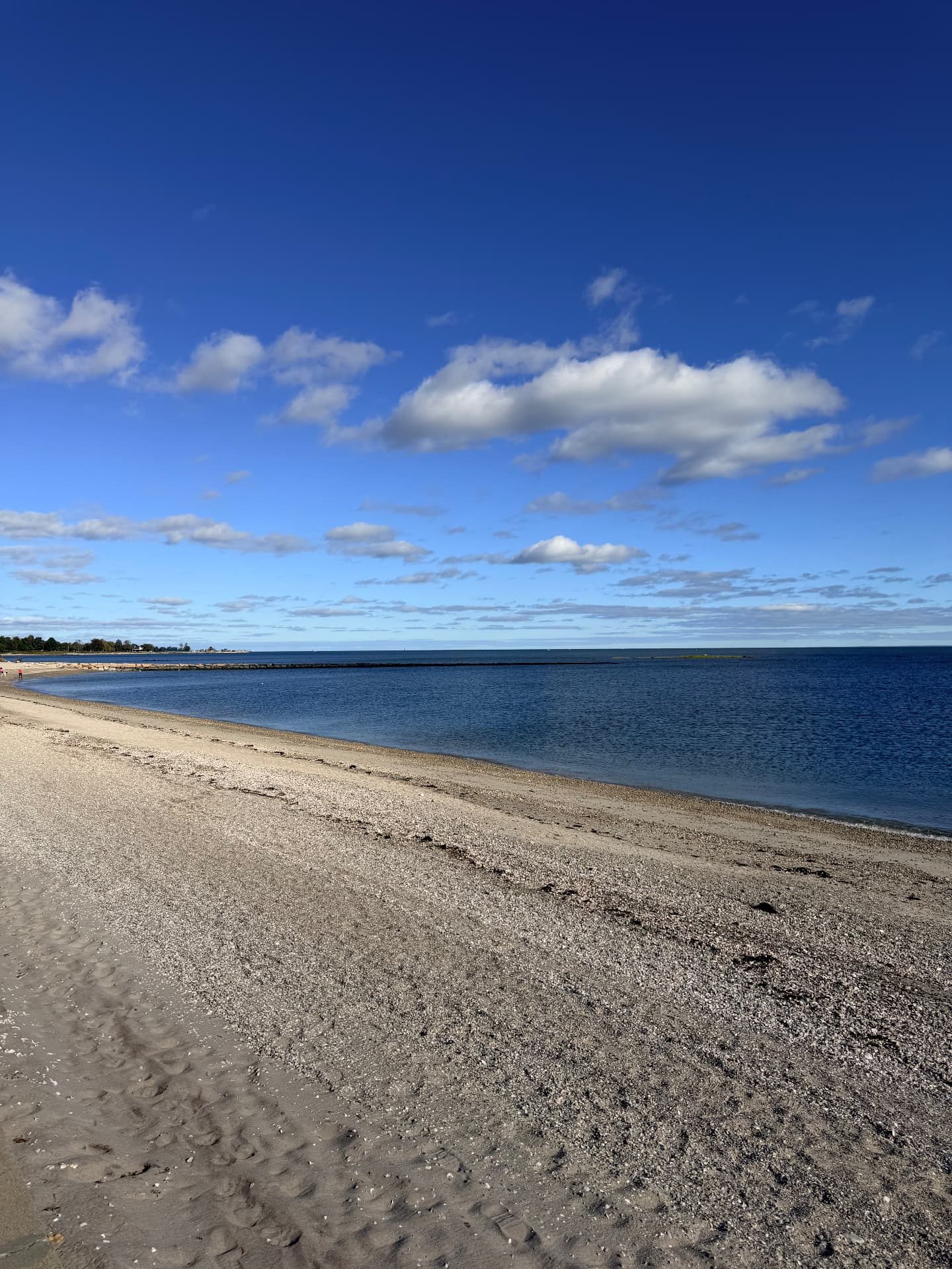 Quiet stretch of beach and calm water under a deep blue sky