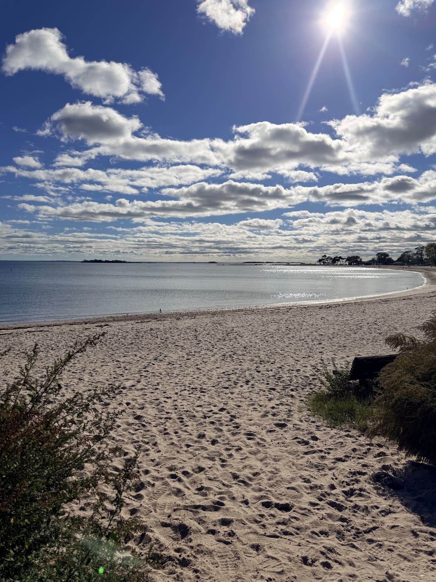Sandy beach curving along Long Island Sound under a blue sky with clouds
